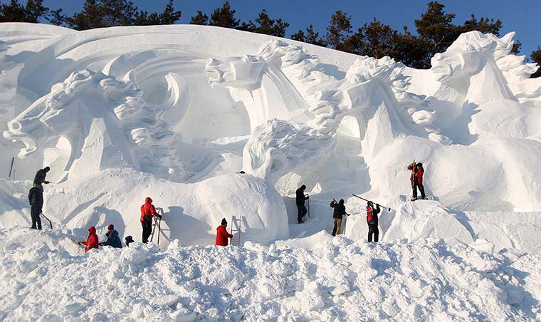 Workers shape a snow sculpture