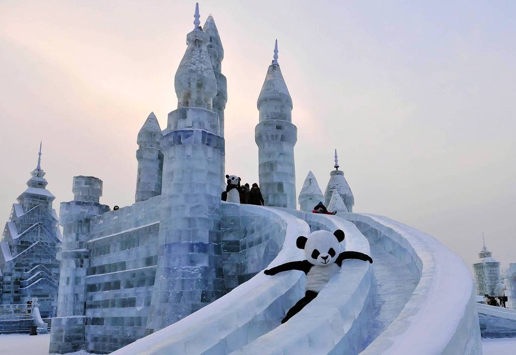 An employee wearing a panda costume slides down from an ice sculpture during the Harbin International Ice and Snow World festival in Harbin